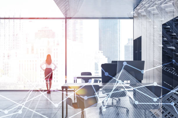 Confident businesswoman standing in panoramic office with wooden bookcases and computer tables. Double exposure of graphs. Concept of stock market. Toned image
